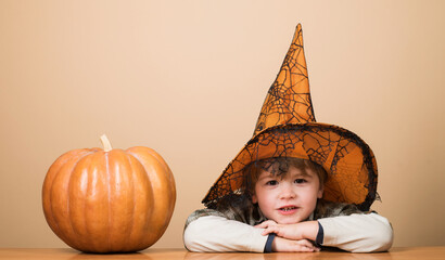 Cute Halloween child with jack-o-lantern pumpkin. Smiling little kid boy in witch hat with Halloween pumpkin. Halloween holiday celebration. Trick or treat. Halloween shopping, sale and discount.