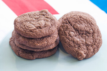 Stack of fresh home baked chocolate cookies with milk chocolate chips on a serving plate
