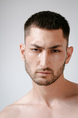 Fototapeta premium Man facial care skin rejuvenation face eye patches. Man facial care. Skin rejuvenation. Cosmetic product advertising. Satisfied caucasian guy applying collagen gel face eye patches on grey background.