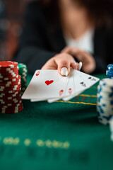 female hand takes poker chips from a pile at a round poker table. risky bets in poker