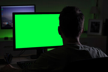 A shot capturing an individual editing photos or videos on a computer, observed from behind or in semi-profile