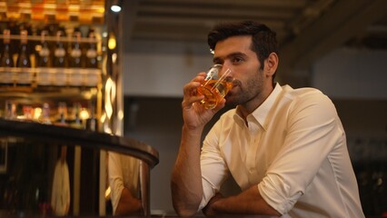 Smart man in white shirt drinking cocktail Old fashioned of special party beverage vibrant waiting for friends or couple at nightclub on Friday meeting night time at luxurious counter bar. Vinosity.