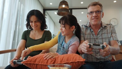 Grandfather, grandmother and granddaughter play console game as hobby. Old senior use technology activity communicate with new generation kid cross generation gap strengthen family bond. Divergence.