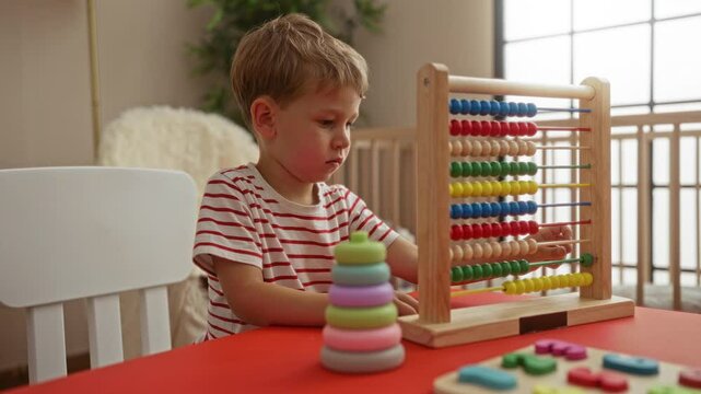 Boy playing with colorful abacus at table indoors showcasing childhood in an indoor setting with educational toys on a kindergarten-like environment