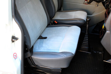 Grey seats with white stitching in old passenger van. Grey leather driver and passenger seats in minivan. Modern van interior. Vans seats row close up. Left view.