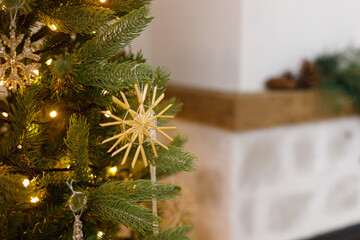 Beautiful decorated christmas tree with straw snowflake, vintage baubles and golden lights. Winter holidays preparation. Atmospheric magical eve. Stylish christmas ornament on tree close up