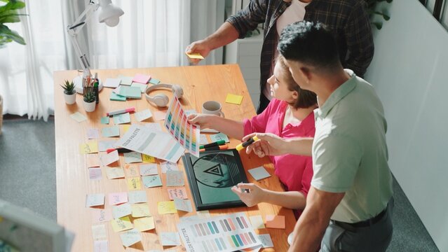 Top view of smart designer holding color palette while project manager looking at design and choosing color for program. Professional businesswoman taking a note while design creative logo. Symposium.