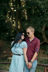 Fototapeta premium A man and a woman are standing next to each other, smiling and holding hands. The man is wearing a plaid shirt and the woman is wearing a blue dress. Scene is happy and romantic