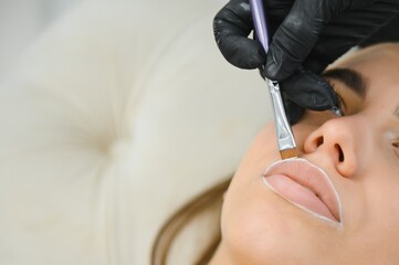 The permanent makeup artist draws a white outline on the lips before the procedure begins