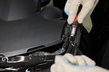 Automobile special workers remove old windscreen or windshield of a car in auto service station garage. Background