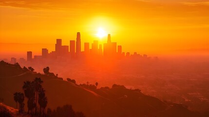 a vibrant sunset over a city skyline, likely Los Angeles, given the distinctive tall buildings. The sun is setting directly behind the cluster of skyscrapers, casting a warm, golden-orange glow across