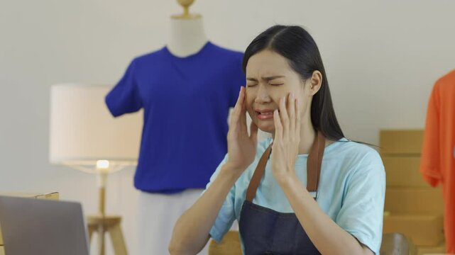 Young asian woman entrepreneur crying at her desk while facing the challenges of running a small business from home