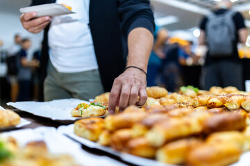 A man selecting pastries at a bustling food festival during a lively afternoon gathering with friends and family