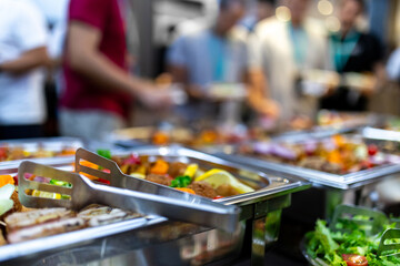 Buffet setup featuring a variety of colorful dishes and fresh salads at a crowded event in the...