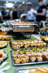 Delicious spread of assorted appetizers and hors d'oeuvres at a bustling event with guests mingling in the background