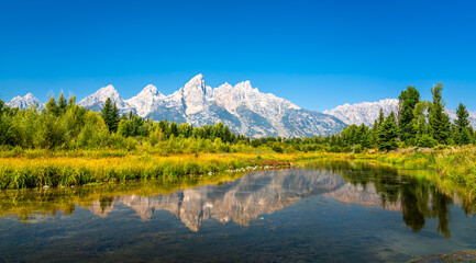 Breathtaking view of the Grand Teton Mountain Range reflecting in the calm waters of the Snake River, captured in Wyoming, United States
