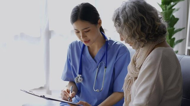 Female doctor in blue scrubs explains medical form details to a senior patient during a consultation in a clinic setting