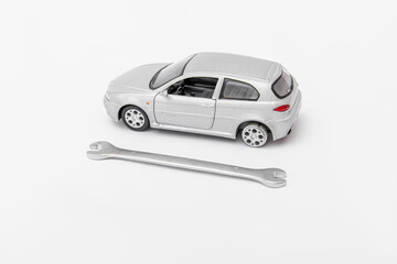 Gray toy car and wrench. Car repair at car service station