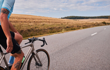 A cyclist rides down a scenic road with rolling hills in the background. The photo captures the sense of freedom and adventure associated with cycling.