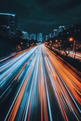 Obraz premium A city street at night with a long line of cars and a few trees. The image has a sense of motion and energy, as the cars are streaking down the road