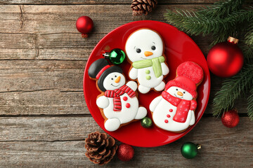 Delicious cookies in shape of snowmen and Christmas decor on wooden table, flat lay. Space for text