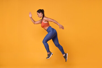 Woman in sportswear running on orange background