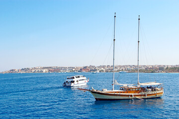 sailboat is sailing in the sea. People swim in sea during summer holidays
