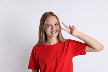 Fototapeta premium Teenage girl showing v-sign on white background