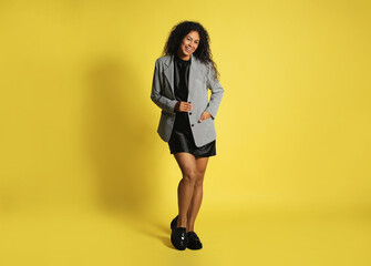 Beautiful woman in stylish jacket on yellow background