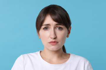 Portrait of frustrated woman on light blue background