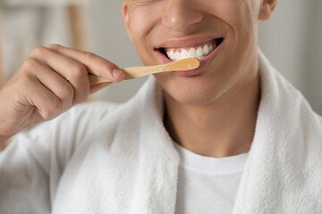 Young man brushing his teeth in bathroom, closeup