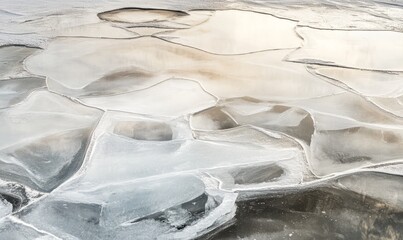 Abstract ice patterns on a frozen lake, reflecting the pale hues of winter dusk