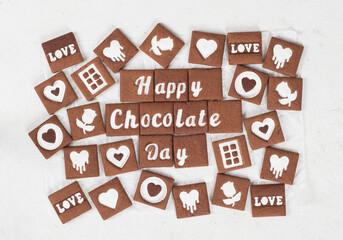 Square chocolate cookies with milk white chocolate filling in the shape of the words Happy Chocolate Day, love, hearts, roses. Top view	