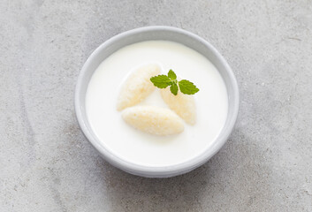 Milk soup with sweet cottage cheese quenelles. Decorated with fresh mint. Top view. Close up