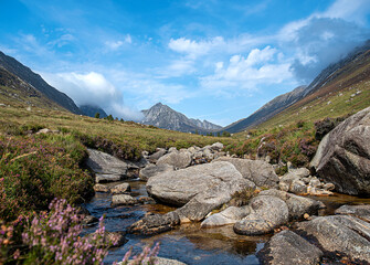 Landscape photography of mountains and valley Glen Rosa, rocky river, viewpoint; blue sky with clouds; travel; hiking and hillwalking, Scotland; UK; Isle of Arran