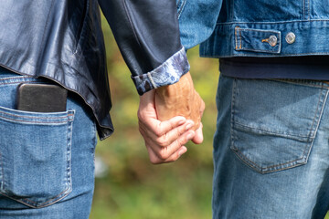 Couple holding hands in jeans, midlife relationship support, love, outdoor togetherness concept