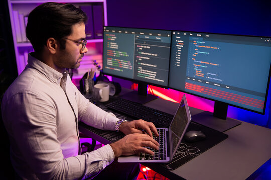 Smart IT developer working on laptop to type searching in software coding system at neon light office room, creating application program update latest version online website database online. Surmise.