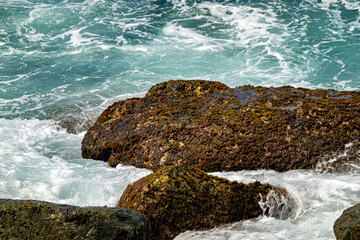 Background themes: Waves breaking on the rocks on a tropical beach.