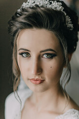 A woman with a tiara on her head. She has green eyes and is wearing red lipstick