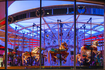 View inside the illuminated Looff Carrousel merry-go-round with it's lilac purple colored lights and vintage horses in downtown Riverfront Park, Spokane, Washington. © Kirk Fisher