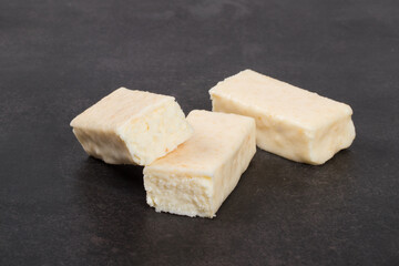Cottage cheese coconut dessert bar in white chocolate glaze. Dark background. Close-up	