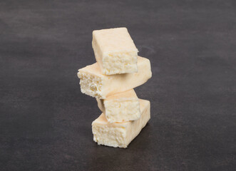 Cottage cheese coconut dessert bar in white chocolate glaze. Dark background. Close-up