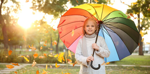 Cute little girl with colorful umbrella in autumn park