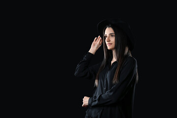 Beautiful young woman with stylish hat on black background