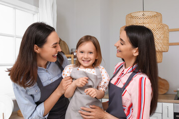Young lesbian couple with adopted little girl in kitchen