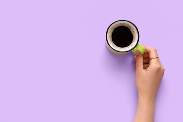 Woman holding cup of hot coffee on lilac background