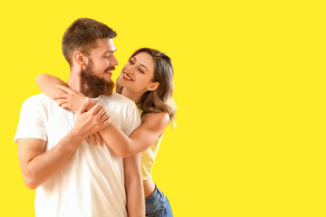 Happy couple in love hugging on yellow background