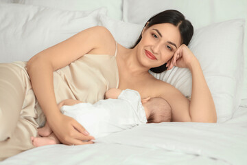 Young woman breastfeeding her baby in bedroom