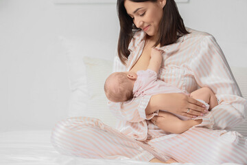 Happy mother breastfeeding her little cute baby in bedroom