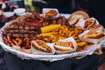 Food festival with food stall kiosk, open-air outdoor fair market, assortment of different traditional European grilled barbecued street food with sausages, bbq, chicken, pork and lamb on a large pan